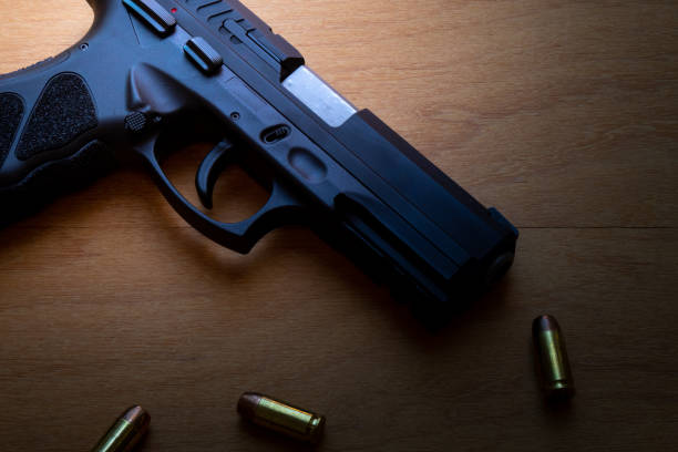 istock firearm, 40 caliber pistol in ammunition on wooden surface. 1310178225