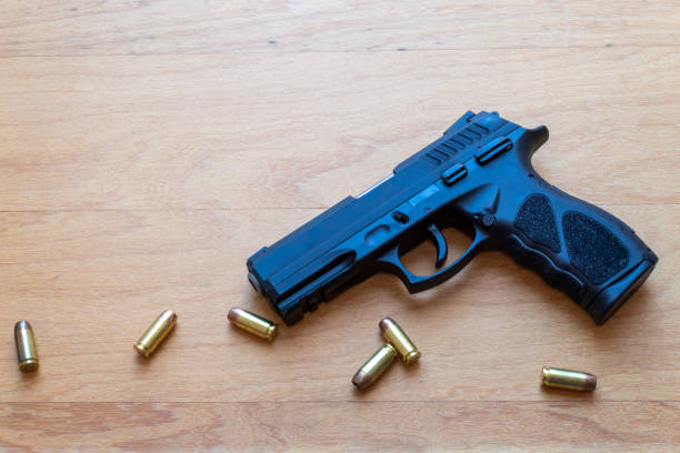 istock firearm, 40 caliber pistol in ammunition on wooden surface. 1310178242