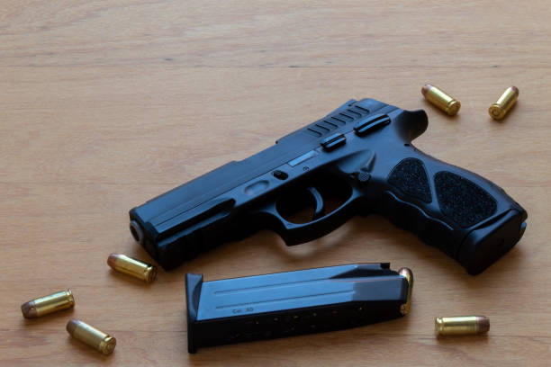 istock firearm, 40 caliber pistol in ammunition on wooden surface. 1310178260