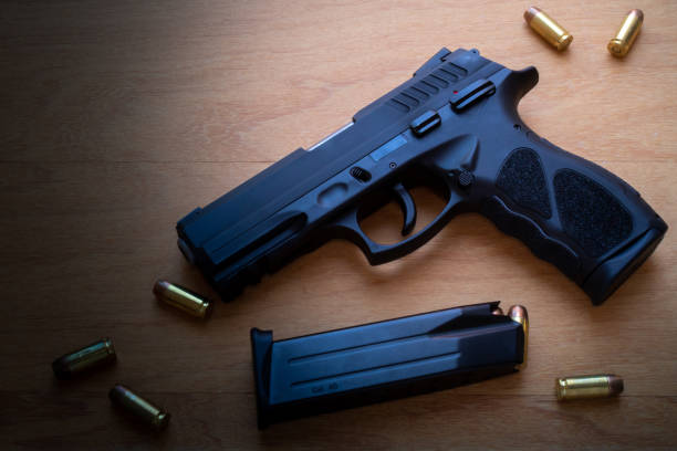 istock firearm, 40 caliber pistol in ammunition on wooden surface. 1310178263