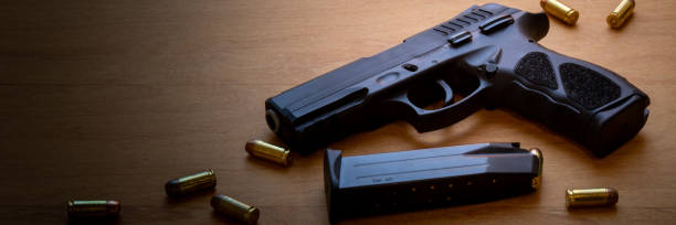 istock firearm, 40 caliber pistol in ammunition on wooden surface. 1310178265