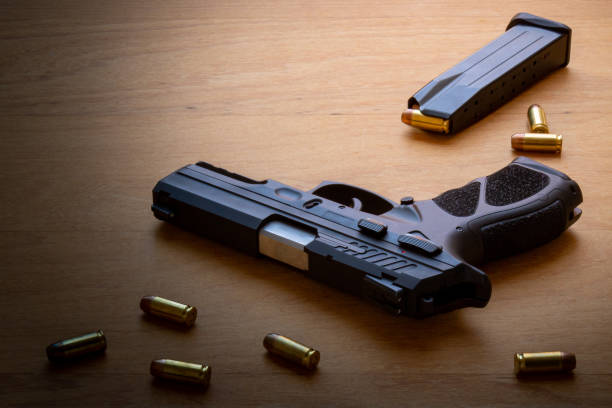 istock firearm, 40 caliber pistol in ammunition on wooden surface. 1310178272