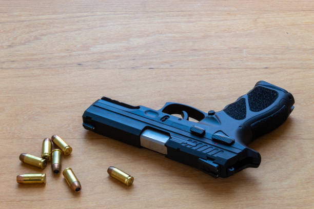 istock firearm, 40 caliber pistol in ammunition on wooden surface. 1310178279