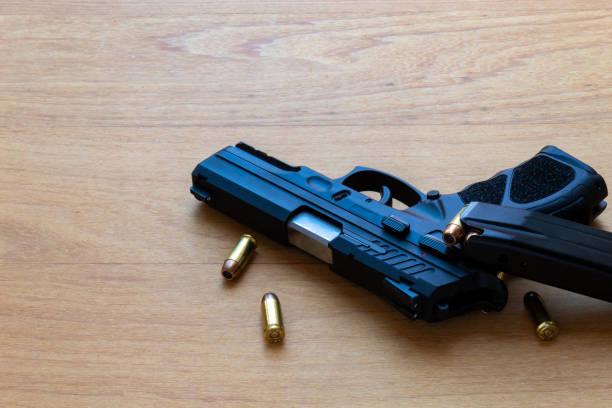 istock firearm, 40 caliber pistol in ammunition on wooden surface. 1310178296