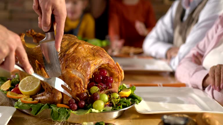 Close up of unrecognizable person carving white meat during dinner for his family.
