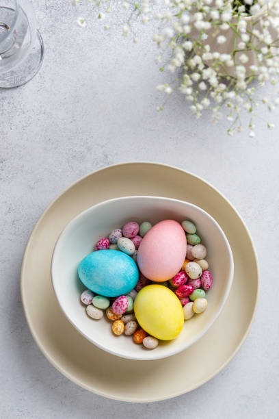 istock Easter table setting with colored eggs and colorful speckled chocolates on ceramic plate