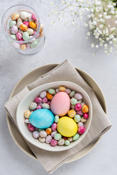 Easter table setting with colored eggs and colorful speckled chocolates on ceramic plate