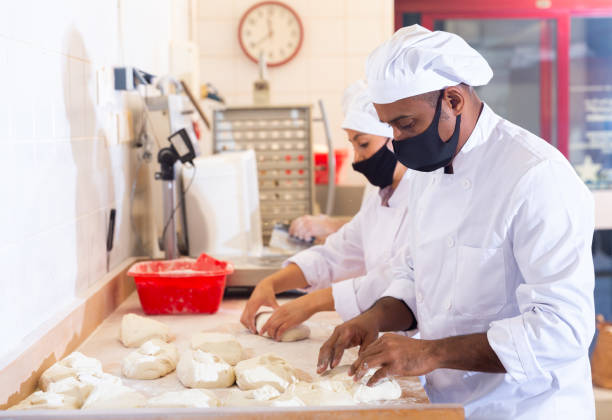 istock Male and female baker in protective mask working together in bakery 1310180683