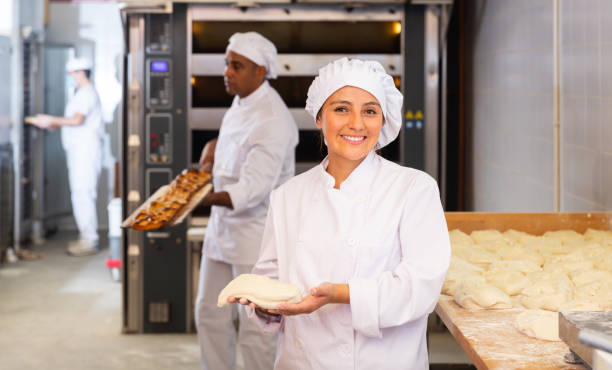 istock Smiling female baker holding raw dough in bakery workshop 1310180715