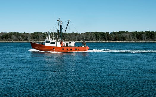 An old red and white fishing trawler passing through Cape Cod Canal