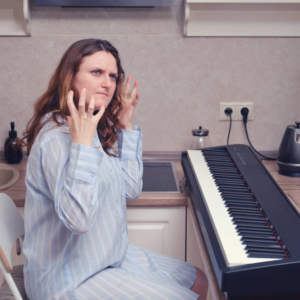 istock Angry female pianist in a blue nightie viciously raised her hands, problems playing the piano 1310183621