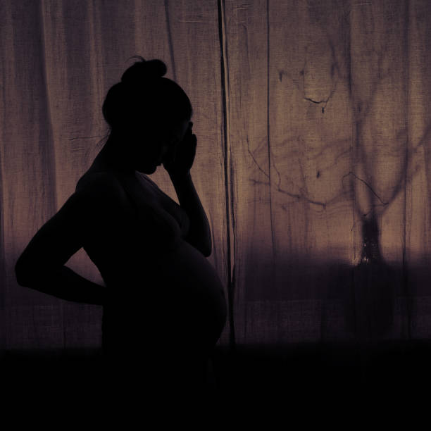 Silhouette Of A Woman Holding Her Head During Pregnancy Pregnant Woman In Sadness At The Window Stock Photo - Download Image Now - iStock