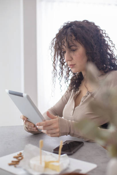 istock Smiling modern brunette woman surfing internet use tablet sitting at table in minimalistic interior 1310189107