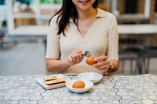 Image of a young Chinese woman having traditional style Malaysian breakfast in restaurant