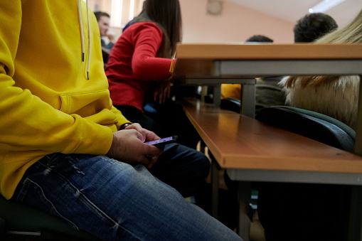 the student hides and uses a smartphone to cheat in class