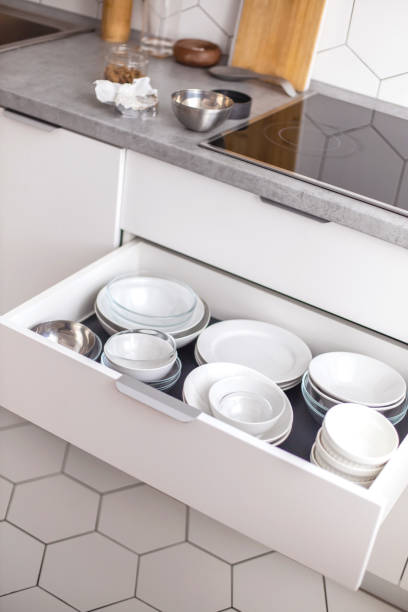 istock Comfortable white gray kitchen interior open box full of various crockery porcelain or glass plates 1310191383