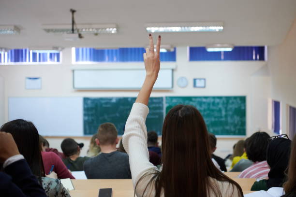 istock female student sitting in the class and raising hand up 1310195959