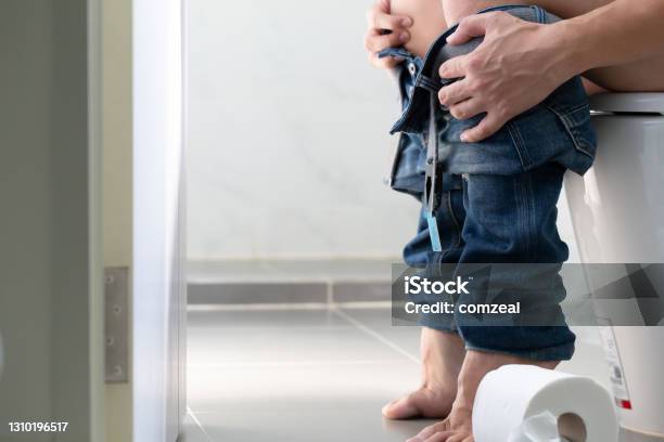 Man Sitting On Toilet With Toilet Paper In Restroom Constipation And Hemorrhoids Concept Stock Photo - Download Image Now