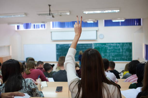 istock female student sitting in the class and raising hand up 1310196827