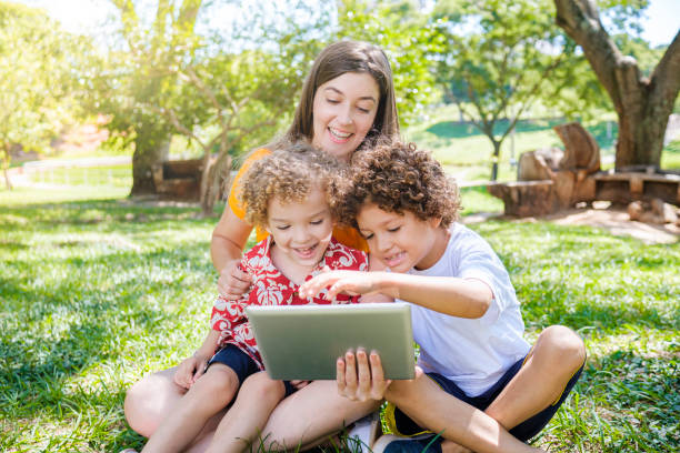 Family in park using technology at the moment of connection stock photo