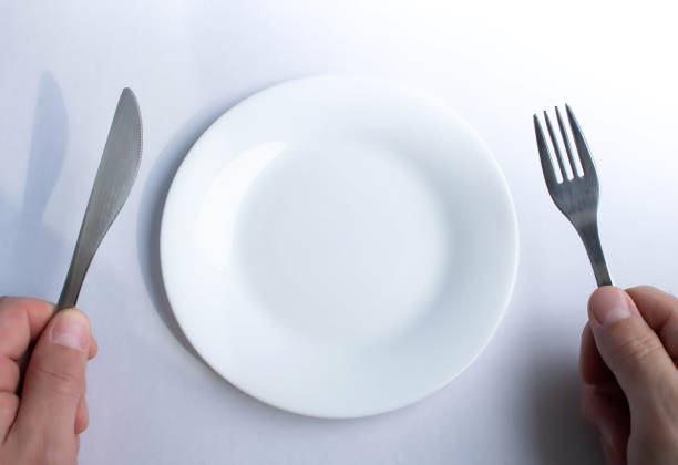 istock Fork and knife in hand against the background of an empty plate. 1310200758