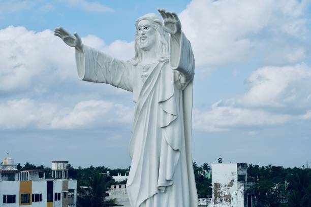 istock Jesus statue standing and blessing with both the hands against blue sky background. 1310201710