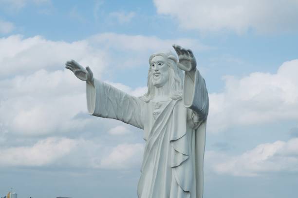 istock Jesus statue standing and blessing with both the hands against blue sky background. 1310202356
