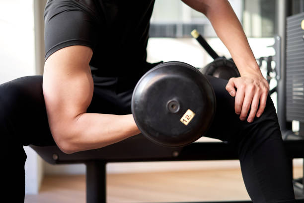 Asian man doing dumbbell curls in a training gym