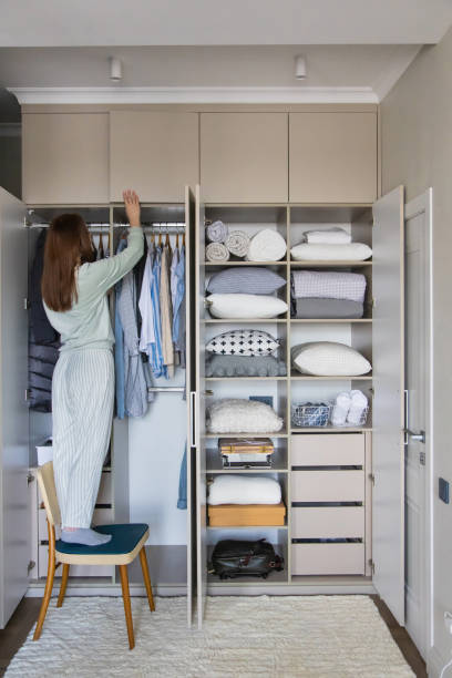 istock Joyful female putting box on shelf in cupboard enjoying housework at wardrobe organizing storage 1310204053