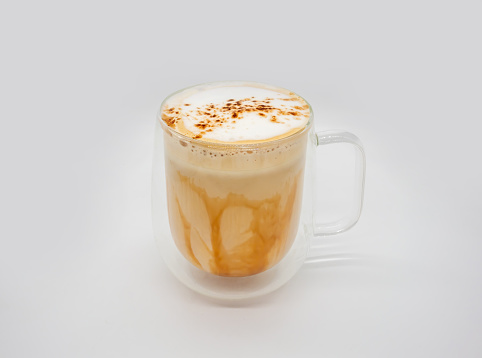 Hot coffee with milky foam sprinkle with cocoa power for decoration in double wall glass isolated on white background.