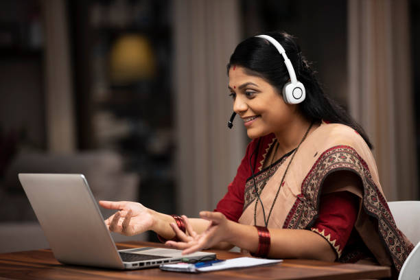 representante de atención al cliente de mujer india sentada en silla en casa:- foto de archivo - indian culture women india indian ethnicity fotografías e imágenes de stock