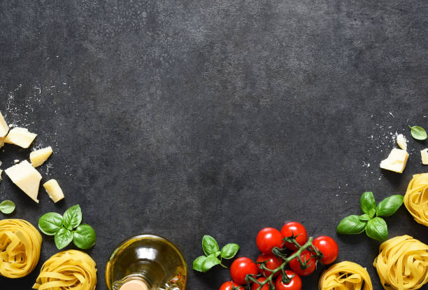 istock Tagliatele pasta, tomatoes, basil and parmesan cheese on a black concrete background. Ingredients for pasta with text space. Layout. 1310210782