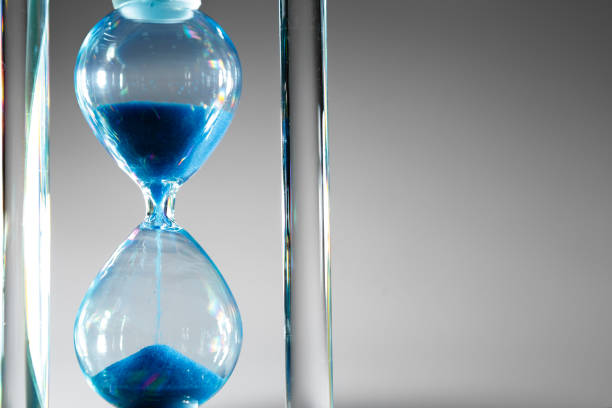 istock Blue hourglass on gray background close up 1310218017