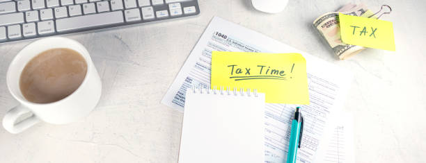 banner with Tax time - Notification of need to file tax returns, tax form at accountant's workplace. Top view of notepad, stickers, cup of coffee and money on table stock photo