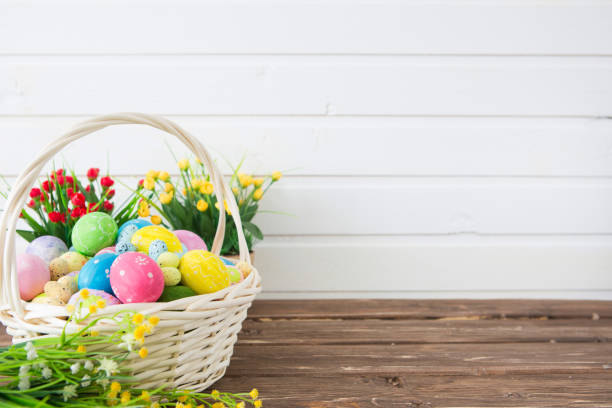 istock Colored easter eggs in the basket and spring flowers on wooden background. Greeting card 1310220117