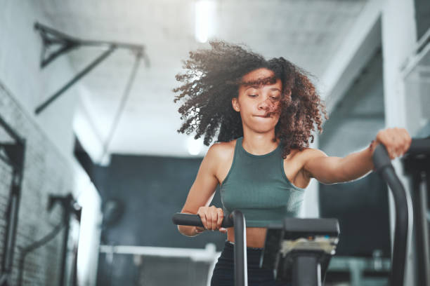 Everything is hard before it is easy Shot of a young woman working out on an exercise bike in a gym spin bike stock pictures, royalty-free photos & images