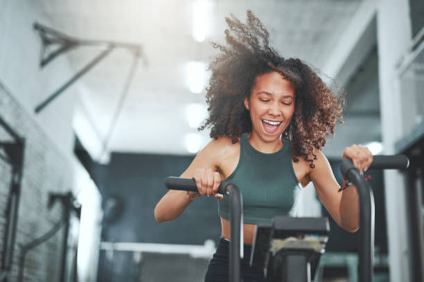 You will burn and firm at the same time Shot of a young woman working out on an exercise bike in a gym exercise bike stock pictures, royalty-free photos & images