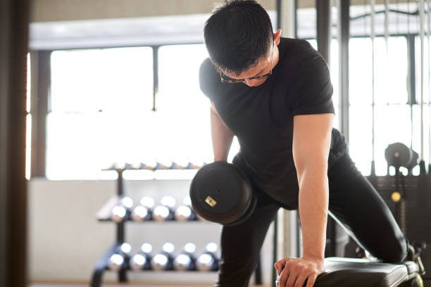 istock Asian man doing one-handed bent-over row in a training gym 1310222272