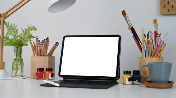 istock Mock up computer tablet, coffee cup, stylus pen and painting tools at artist or creative designer workplace. 1310227010