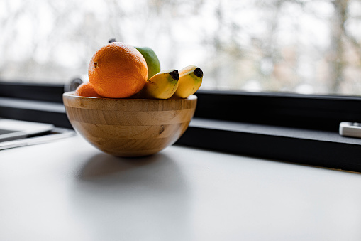 Close up of a bowl with apples, oranges and bananas on the table. Copy space.