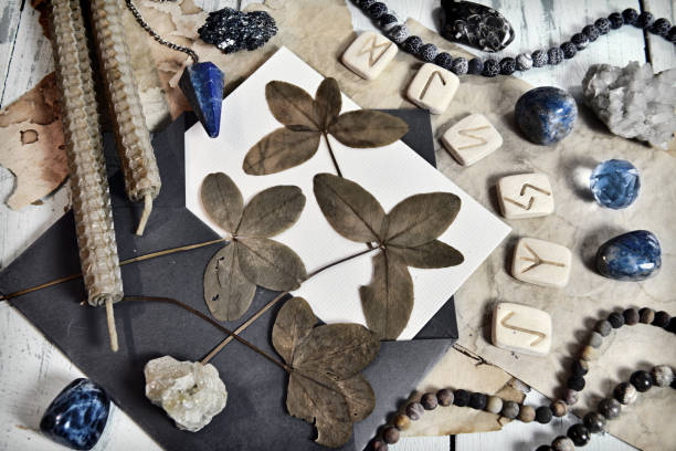 Grunge still life with four leaf clover, runes, candles and crystals on witch table.