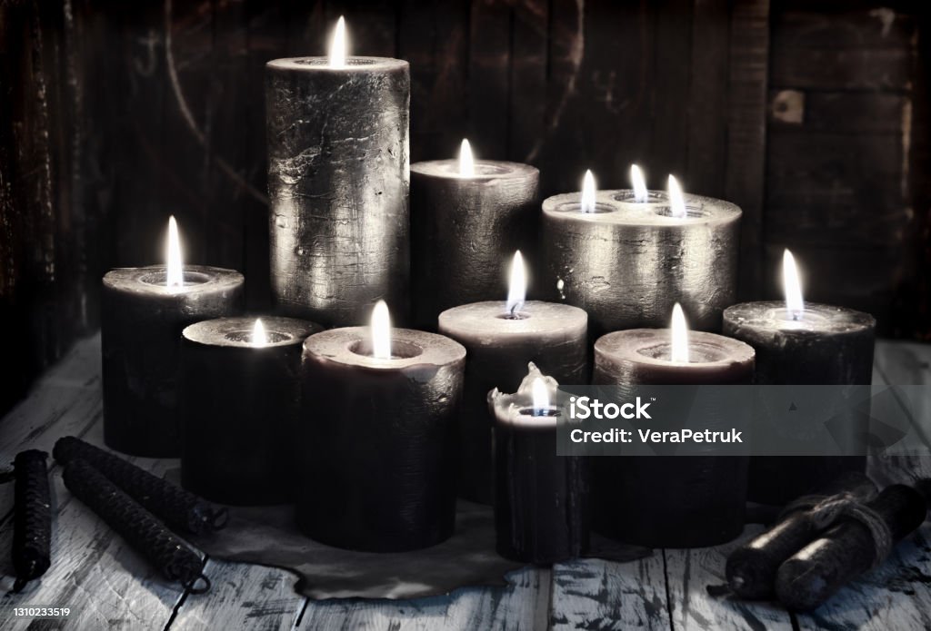 Group of black burning candles on witch table, grunge style. Group of black burning candles on witch table, grunge style.  Esoteric, gothic and occult background, Halloween mystic concept. Candle Stock Photo