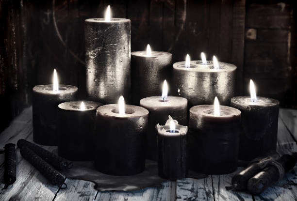 Group of black burning candles on witch table, grunge style. stock photo