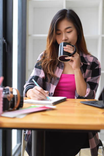 istock Portrait of female freelancer drinking coffee break while writing on blank notebook 1310233529