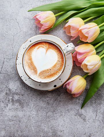 Spring tulips and cup of coffee on a concrete background