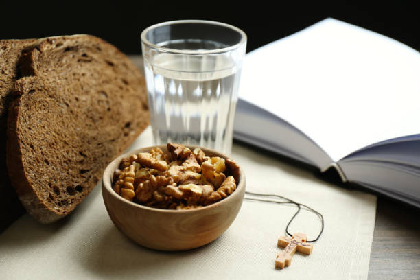 brot, walnüsse, wasser, bibel und kruzifix auf dem tisch. große fastenzeit - fasten stock-fotos und bilder