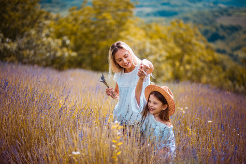 Loving mom playing outside with her daughter. Happy young father and daughter having fun while running in spring day at the park. Blooming trees