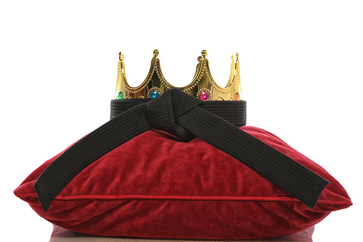 Marital arts black belt with crown on a pillow.
