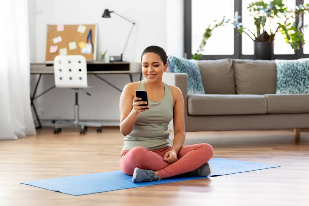 istock woman with smartphone sits on exercise mat at home 1310238756
