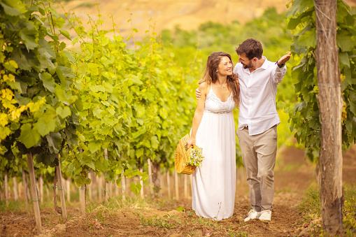 Couple standing and talking in vineyard.